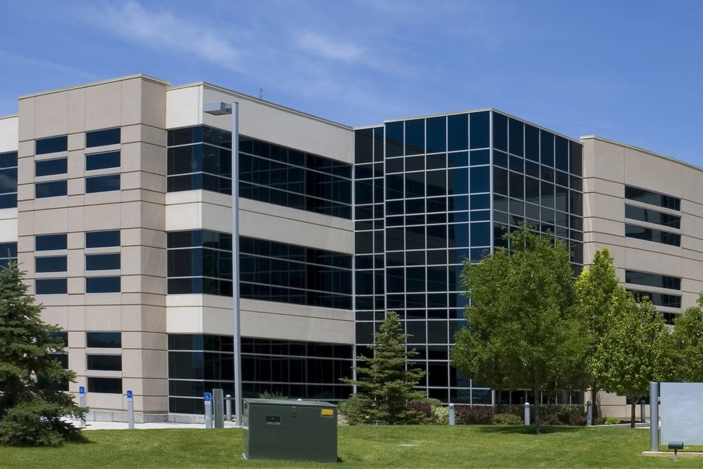 Modern office building with glass windows and greenery, serviced by a commercial moving company in NYC.