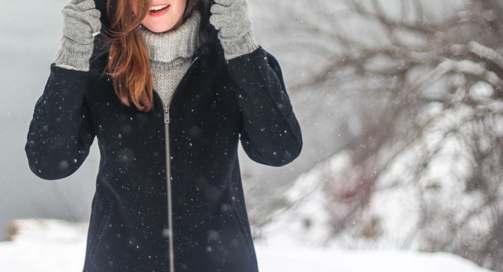 smiling woman wearing winter clothes in snow