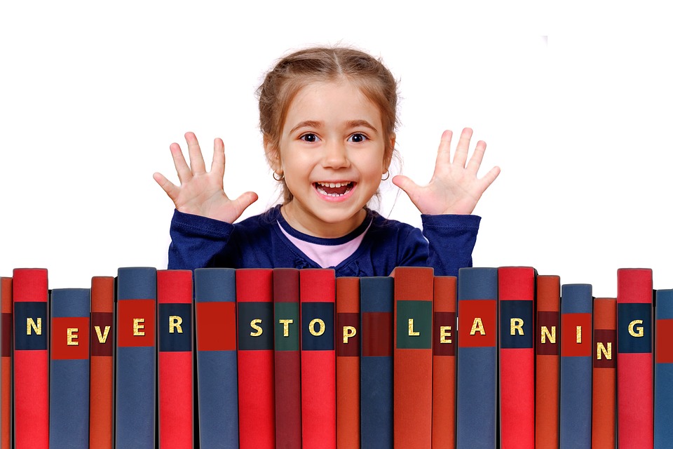 Happy Child With Books That Say "Never Stop Learning"