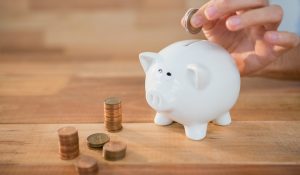 person putting coins into piggy bank