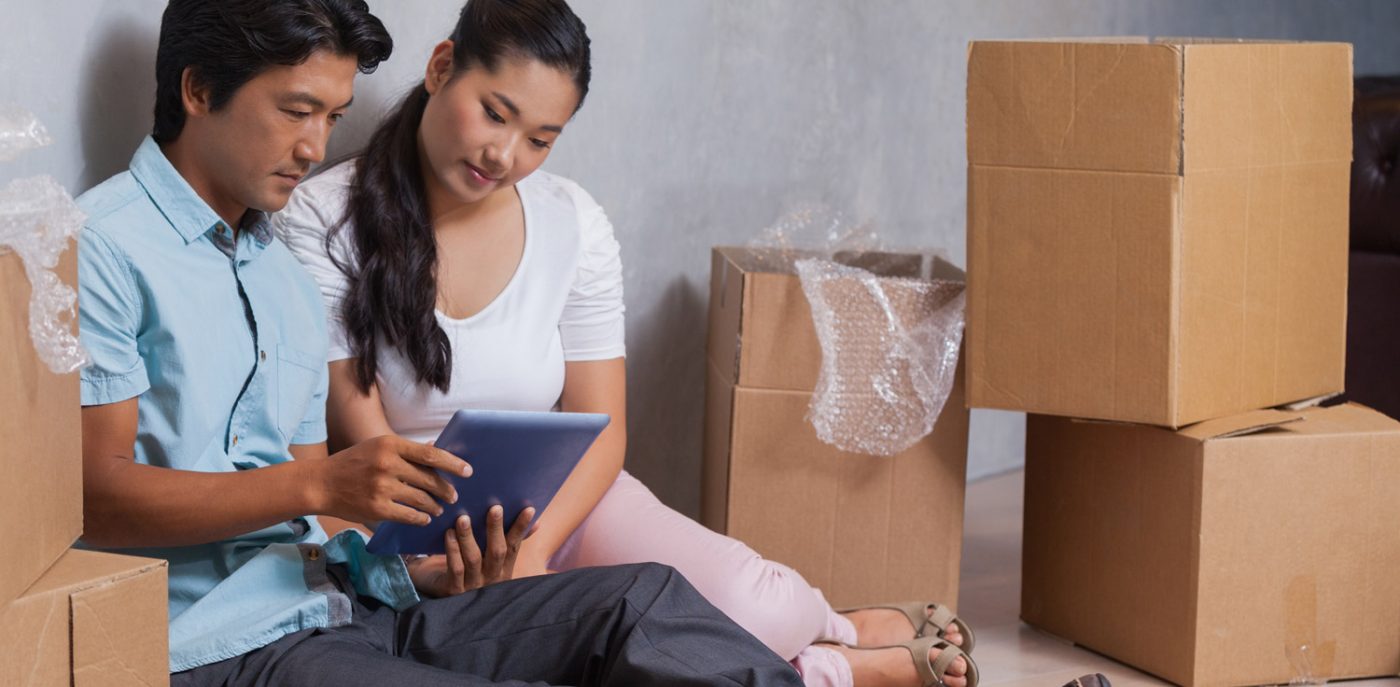 Couple sitting on the floor, packing belongings into boxes