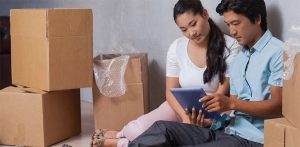 couple sitting on floor with moving boxes around them