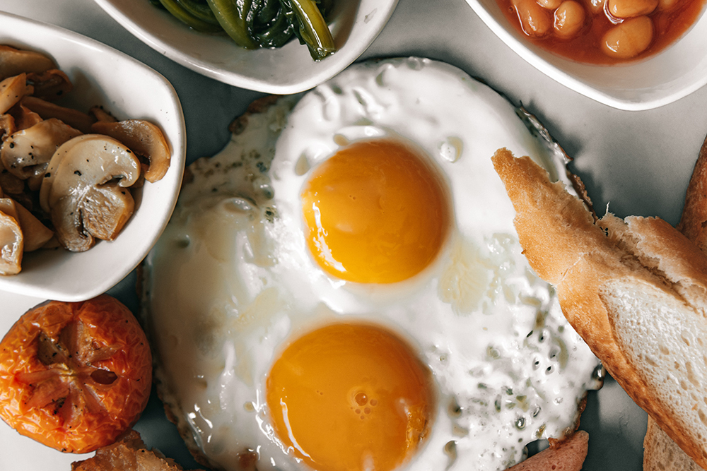 A spread of vegetables, fried eggs, and bread