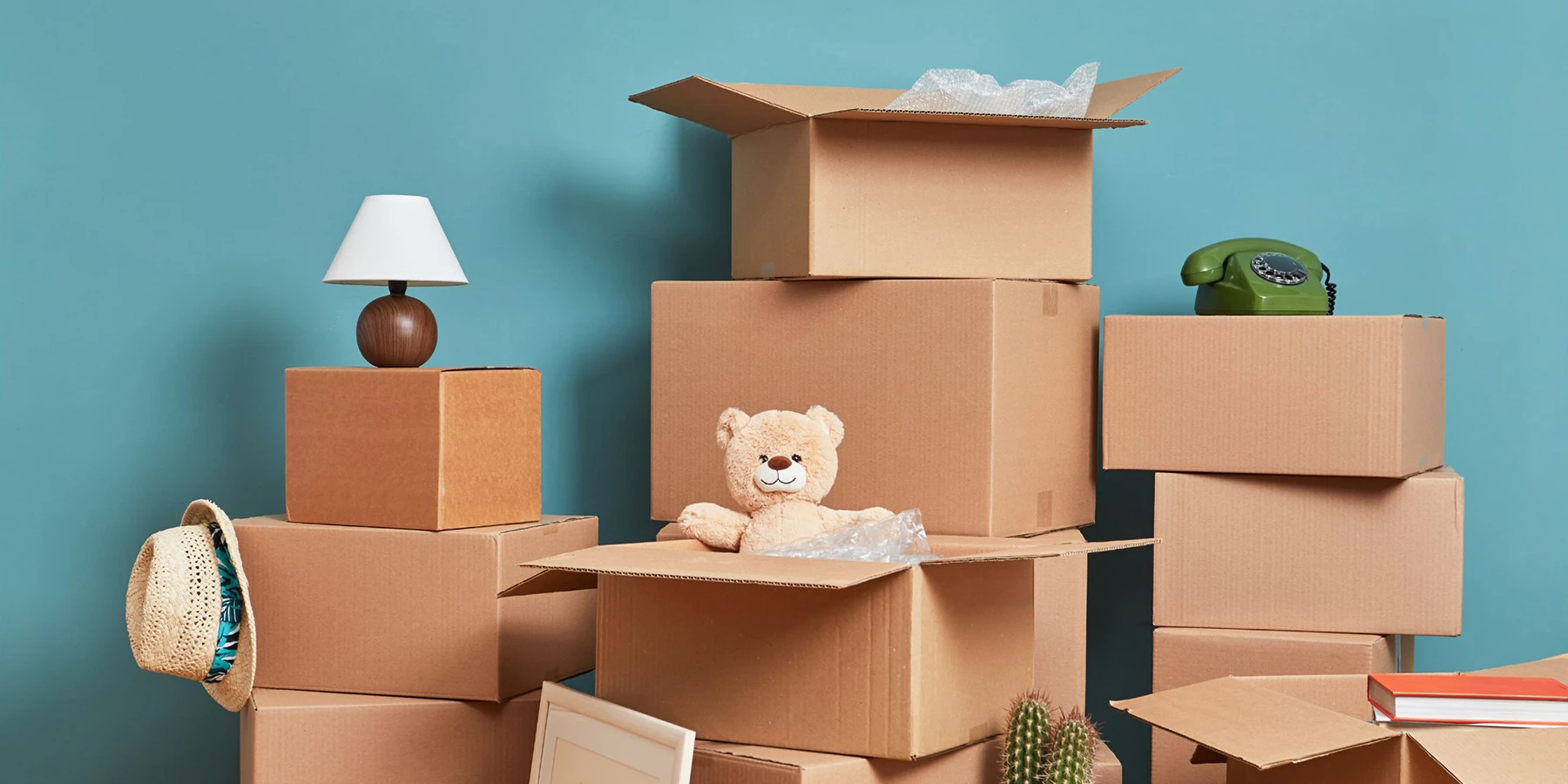 Stacks of boxes and household items against a blue wall that are ready to be moved to storage in NYC.